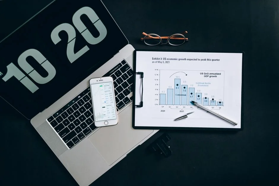 Overhead view of business chart with red notebook and colored pencils on table.
